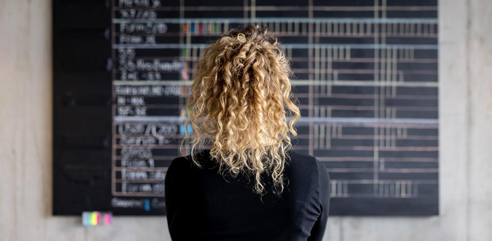 Business women looking at a project management calendar on a chalkboard in her office.