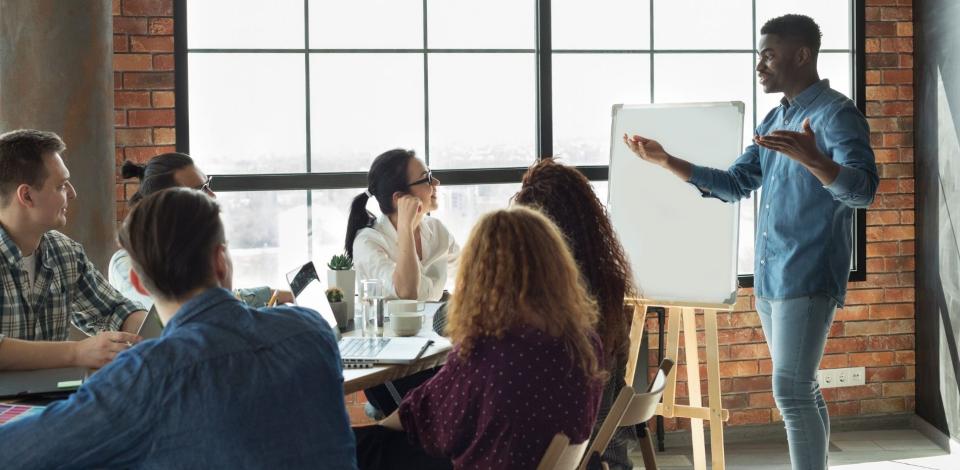 Team leader is addressing employees in loft office using white board