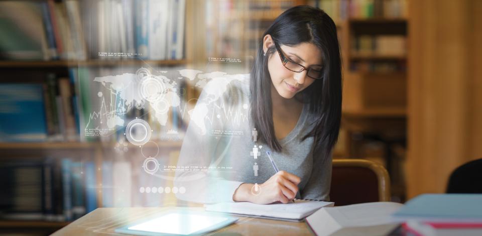 Woman looking over book with digital images in front of her