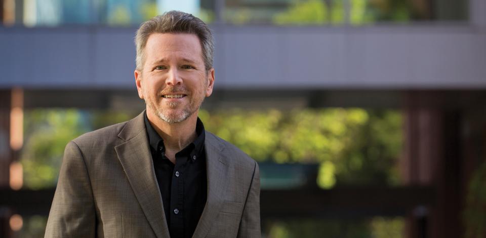 Glenn Hopkins smiling at camera. The background behind him is blurred.