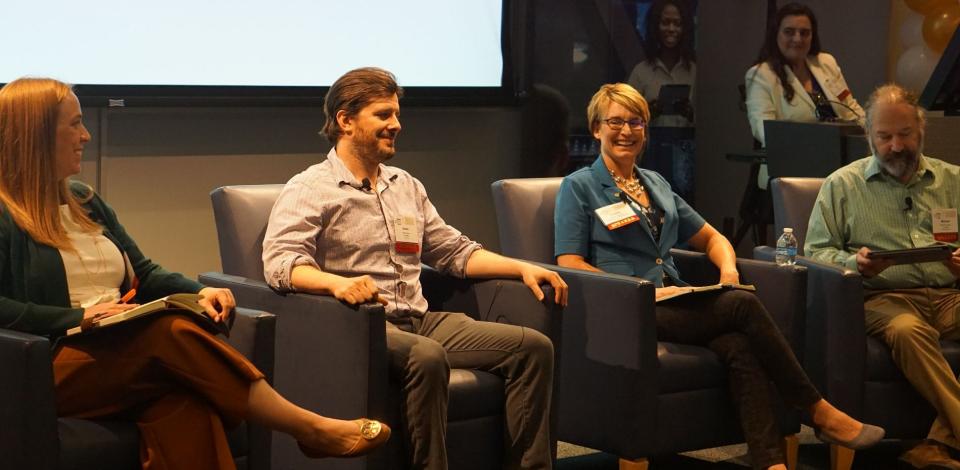 Four individuals sit at front of the room to discuss early lessons learned as part of the Affordable Degrees-at-Scale Symposium.