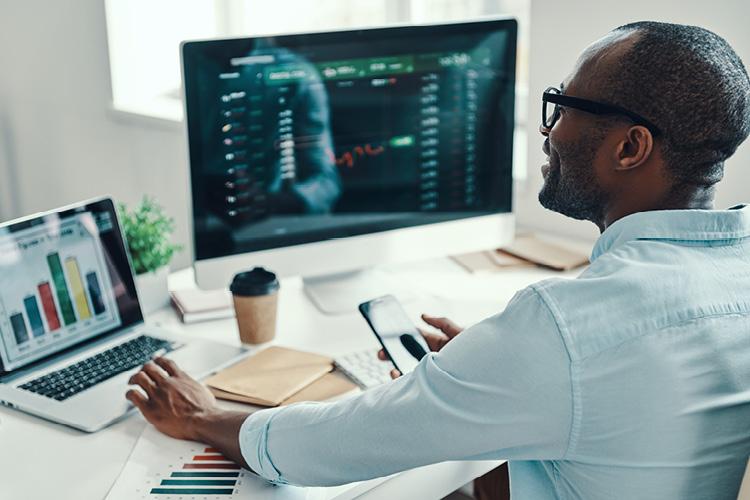 Business professional analyzing data on computer screens