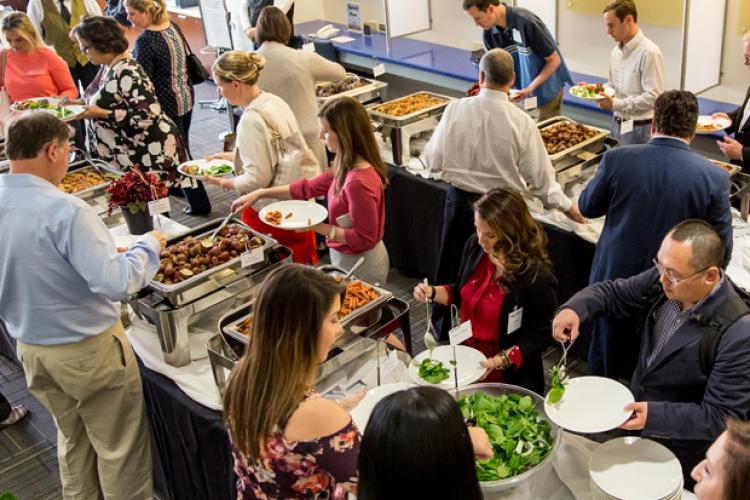 Individuals serving themselves food in a buffet line