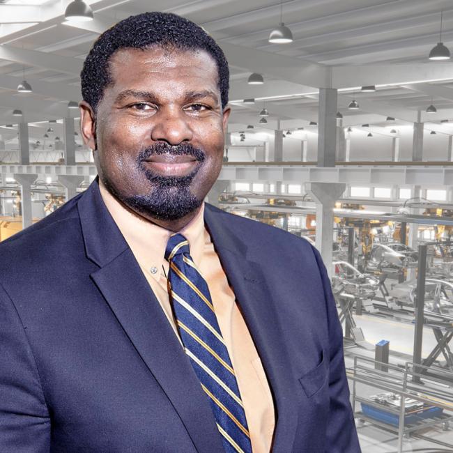 Professional headshot of Chuck Easley set on a robotics factory background. 