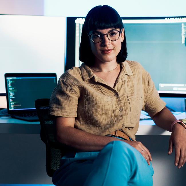 A woman sitting in front of computer screens at an office.