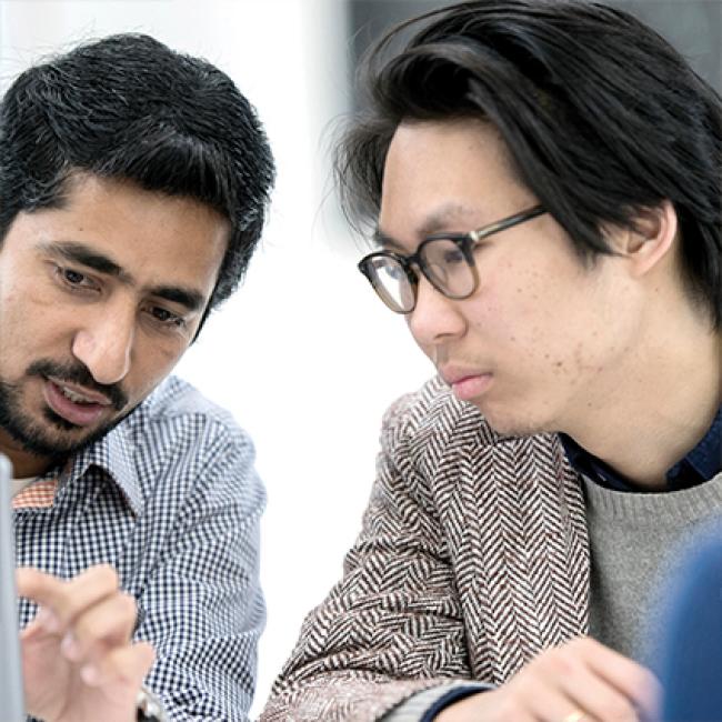 Two male adult learners working on a project in class