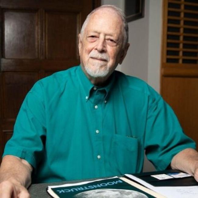 Bob Macdonald, online masters in analytics student, sits at table with historic moon landing documents in front of him.