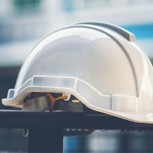 White and yellow helmet with construction water,gloves and radio that are placed on steel house fence.